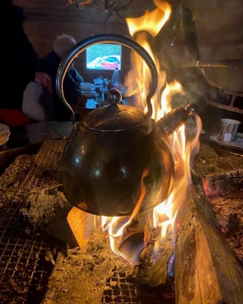 Kaffepanna som hänger över den öppna elden inne i kåtan