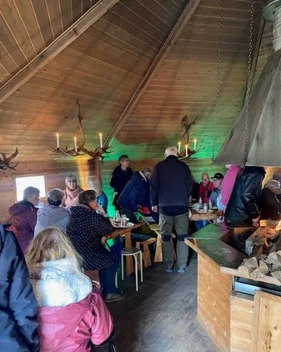Gäster som sitter runt de långa borden inne i den åttkantiga kåtan