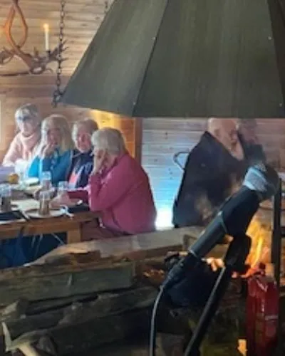 Gäster som äter vid långbordet medan elden brinner i kåtan