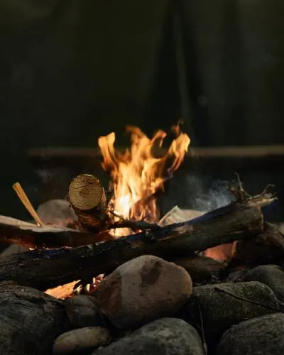Brasa av ved och stenar som brinner utanför kåtan i skymningen